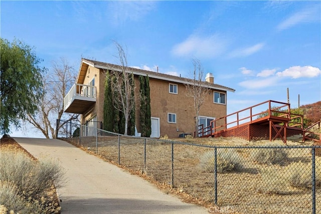 rear view of house with a fenced front yard, a chimney, and stucco siding