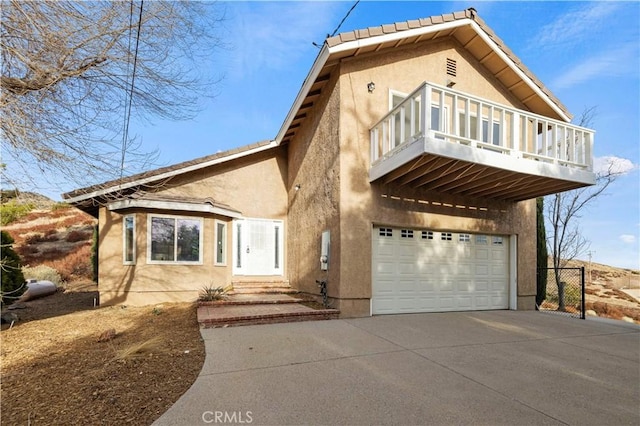 view of front facade featuring a tile roof, stucco siding, a garage, a balcony, and driveway