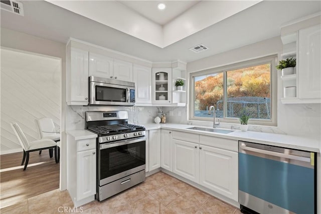 kitchen with open shelves, visible vents, appliances with stainless steel finishes, and a sink