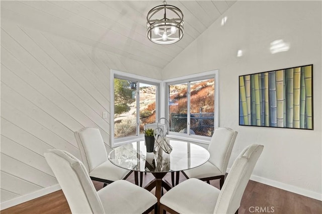 dining room featuring high vaulted ceiling, dark hardwood / wood-style floors, wooden walls, and a notable chandelier