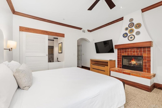 bedroom featuring ceiling fan, ornamental molding, and a tile fireplace