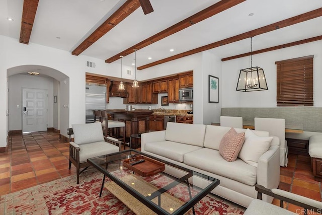 tiled living room featuring an inviting chandelier, sink, and beamed ceiling