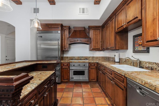 kitchen with premium range hood, stainless steel appliances, sink, and hanging light fixtures