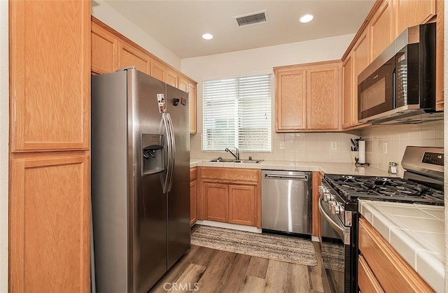 kitchen featuring dark wood-type flooring, sink, tile countertops, appliances with stainless steel finishes, and decorative backsplash