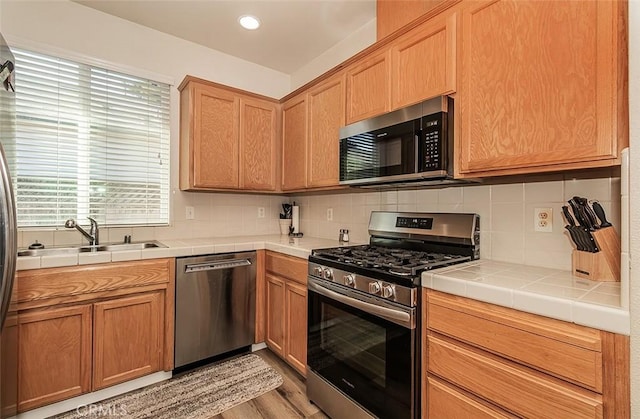 kitchen with stainless steel appliances, tasteful backsplash, sink, and tile countertops