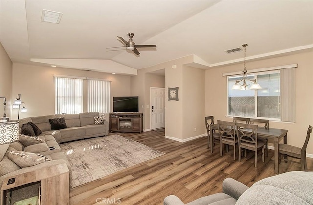 living room featuring ceiling fan with notable chandelier, lofted ceiling, dark hardwood / wood-style floors, and a wealth of natural light