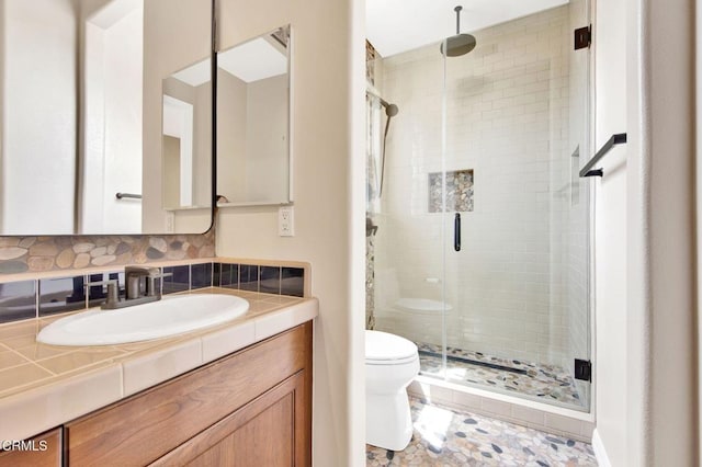 bathroom featuring a shower with door, backsplash, toilet, and vanity