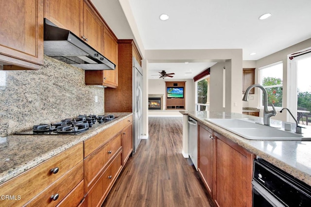 kitchen featuring appliances with stainless steel finishes, dark wood-type flooring, sink, backsplash, and ceiling fan