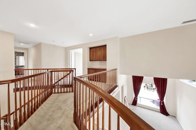 hallway featuring light carpet and an inviting chandelier