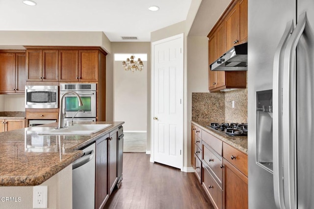 kitchen featuring light stone countertops, appliances with stainless steel finishes, dark hardwood / wood-style flooring, sink, and a center island with sink