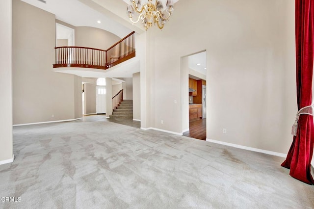 unfurnished living room with carpet floors, a towering ceiling, and an inviting chandelier