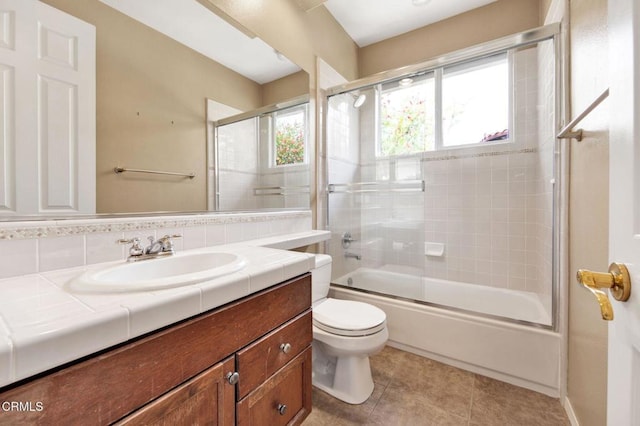 full bathroom with toilet, vanity, backsplash, tile patterned floors, and enclosed tub / shower combo