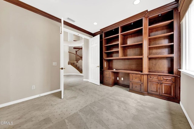 interior space with ornamental molding, light carpet, and built in desk