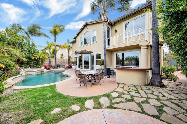 back of house featuring a balcony, a patio area, and a pool with hot tub