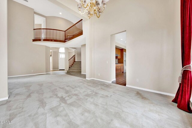 unfurnished living room with a high ceiling, carpet flooring, and a notable chandelier