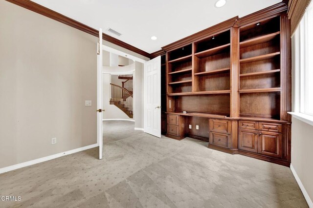 interior space with light carpet, built in desk, and ornamental molding