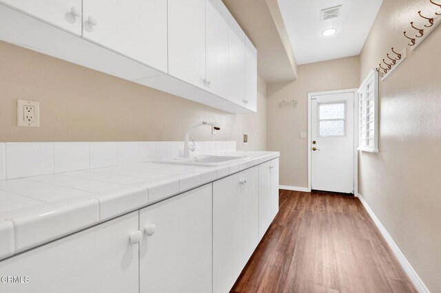 laundry room featuring sink and dark hardwood / wood-style flooring