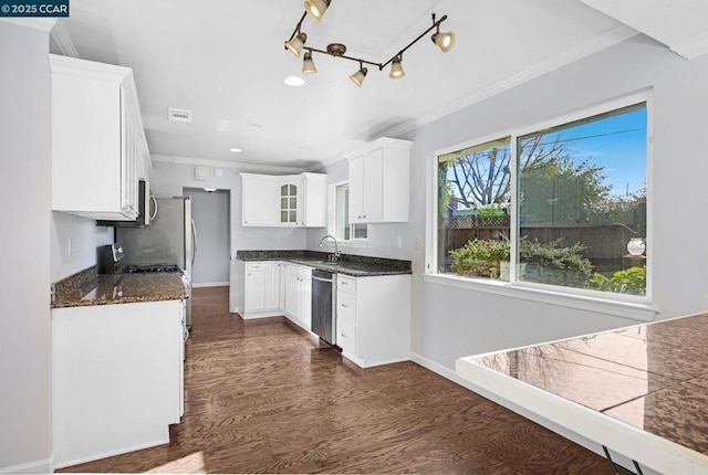 kitchen featuring white cabinetry, stainless steel appliances, dark stone counters, crown molding, and sink