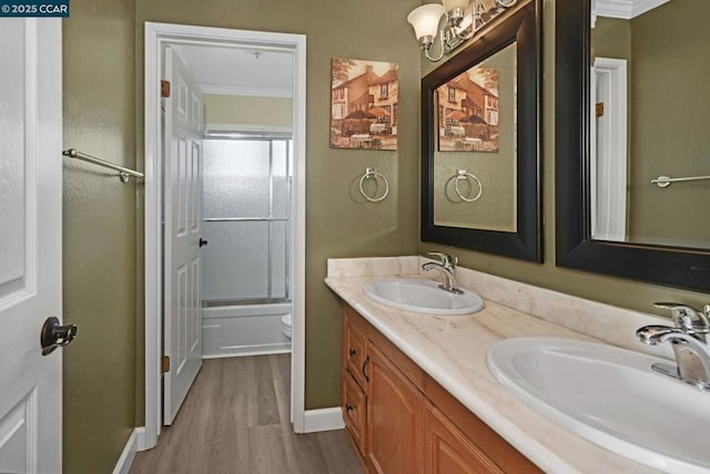 full bathroom with toilet, hardwood / wood-style flooring, crown molding, vanity, and shower / bath combination with glass door