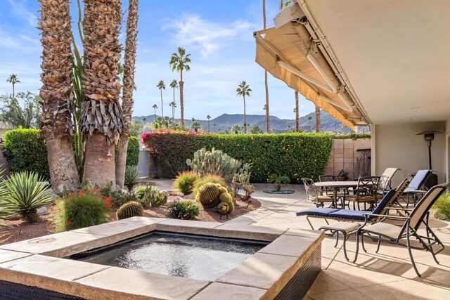 exterior space featuring a mountain view, an in ground hot tub, and a patio