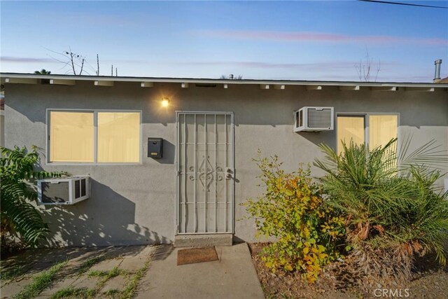 exterior entry at dusk featuring an AC wall unit and a patio