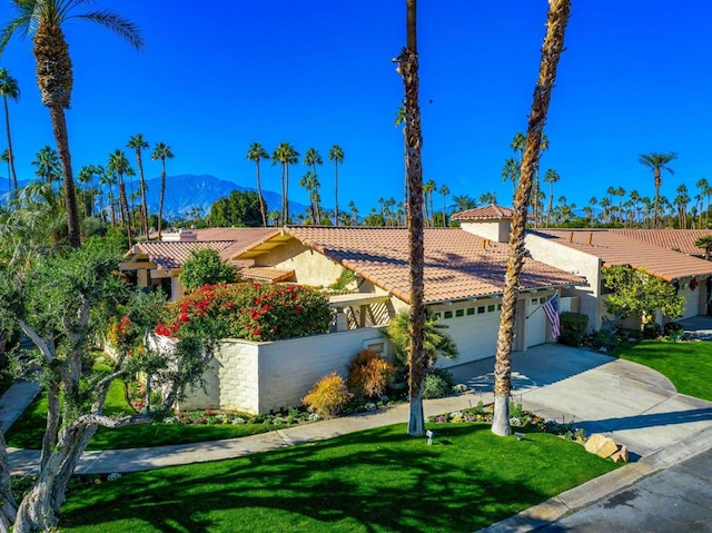 mediterranean / spanish-style house with a garage, a mountain view, and a front yard