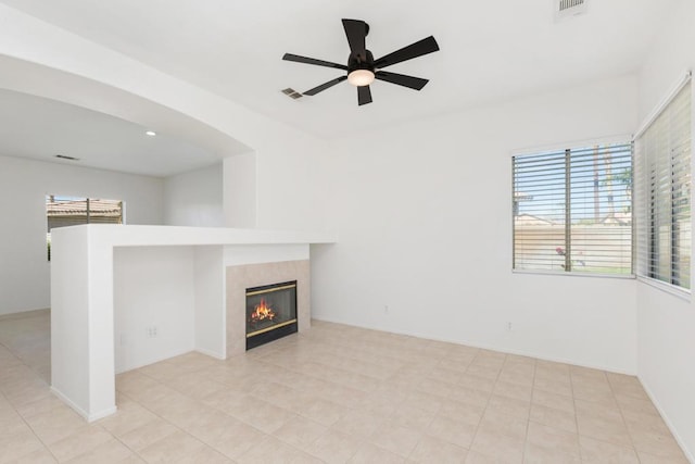 unfurnished living room featuring ceiling fan, a tile fireplace, and light tile patterned flooring