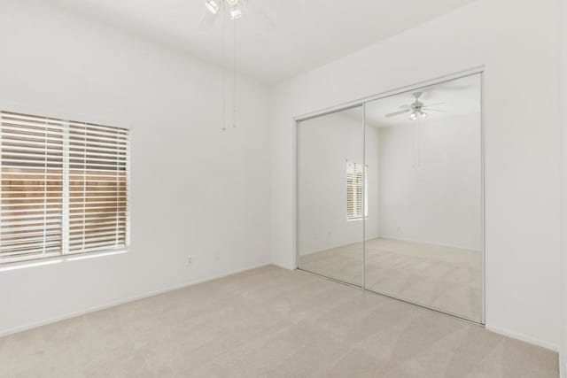 unfurnished bedroom featuring ceiling fan, a closet, and light carpet