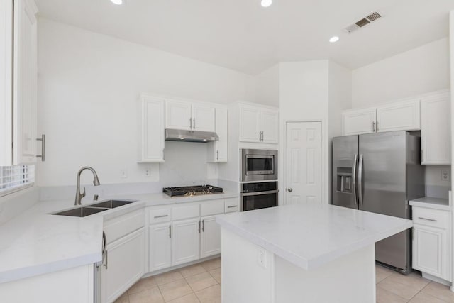 kitchen with white cabinetry, stainless steel appliances, sink, light tile patterned flooring, and light stone counters