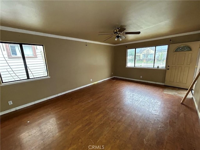 empty room featuring ceiling fan, dark hardwood / wood-style flooring, crown molding, and a wealth of natural light