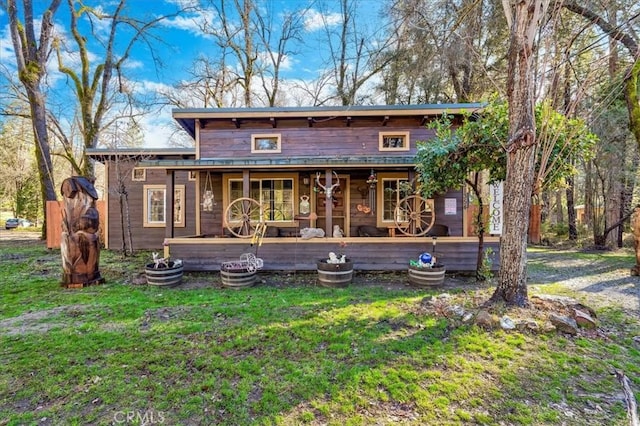 rear view of property featuring covered porch and a yard