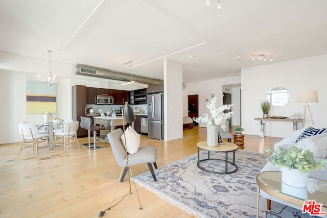 living room featuring a chandelier and light wood-type flooring