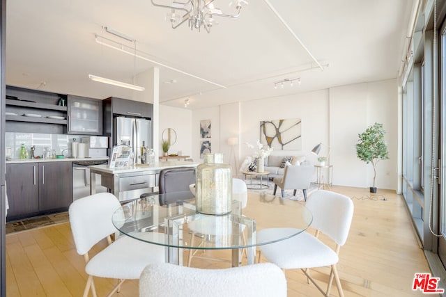 dining area with light hardwood / wood-style floors and an inviting chandelier