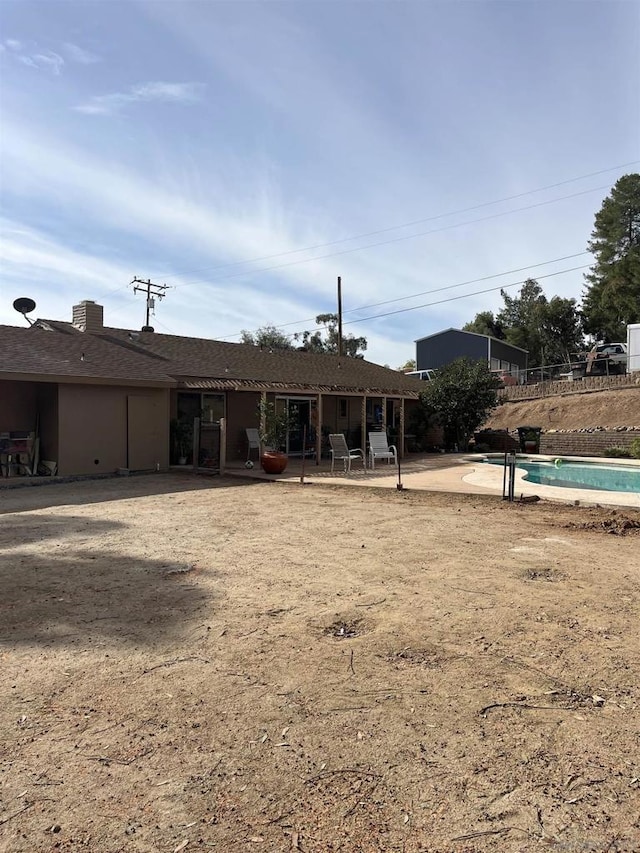 rear view of property with a patio and a fenced in pool