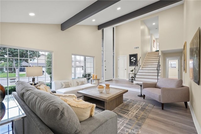 living room featuring light hardwood / wood-style floors, high vaulted ceiling, and beam ceiling