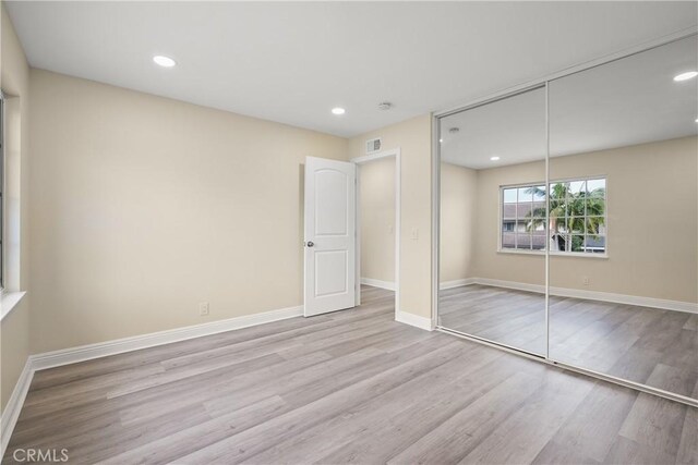 unfurnished bedroom featuring a closet and light wood-type flooring