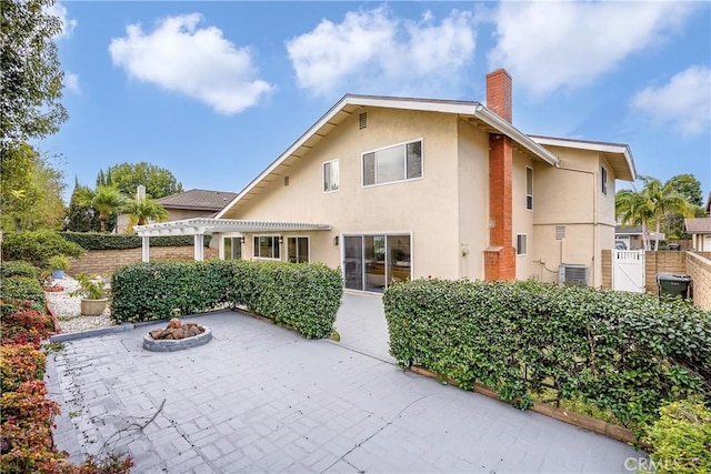 back of property with a pergola, central AC, a fire pit, and a patio