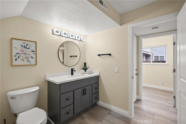 bathroom with hardwood / wood-style flooring, toilet, vanity, and lofted ceiling