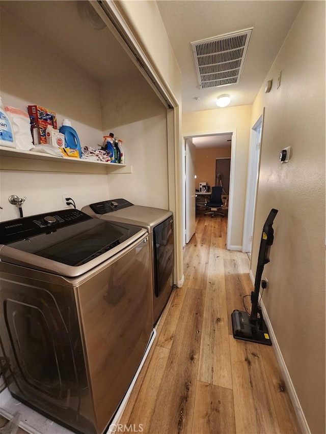 clothes washing area with separate washer and dryer and light hardwood / wood-style flooring