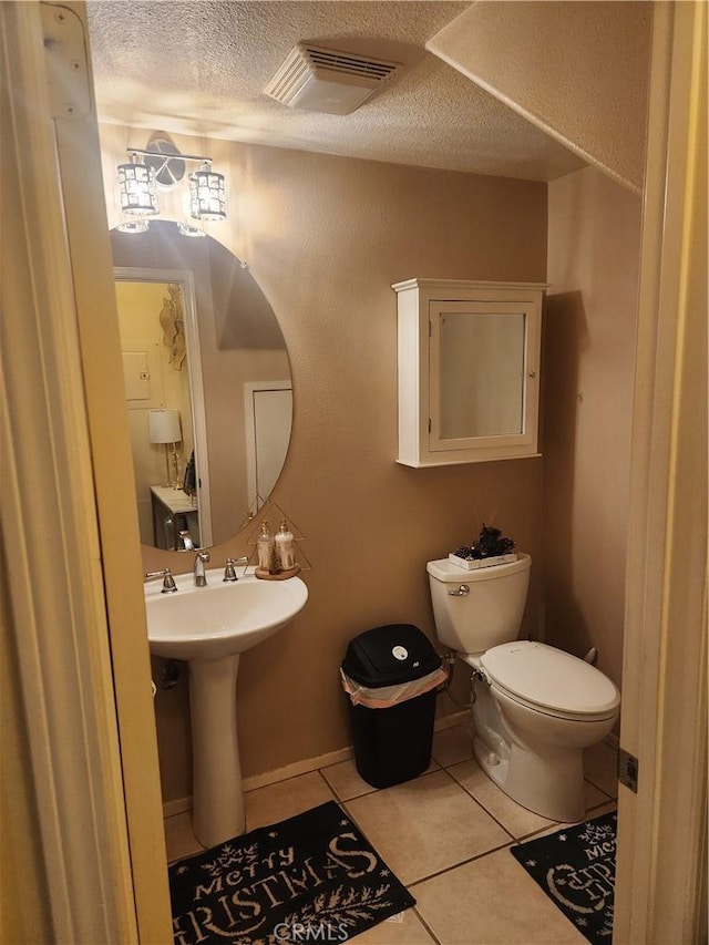 bathroom with toilet, tile patterned flooring, and a textured ceiling