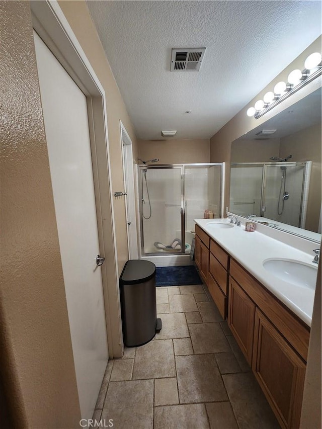 bathroom featuring vanity, a shower with shower door, and a textured ceiling