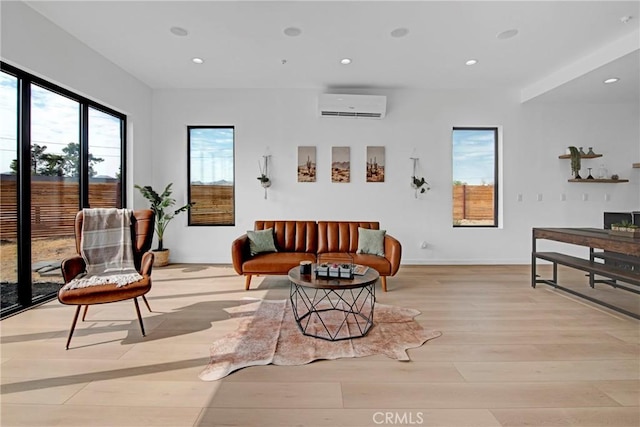 living area with a wall mounted AC and light wood-type flooring