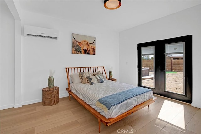 bedroom with light wood-type flooring, access to outside, and a wall mounted air conditioner
