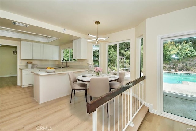 kitchen with white cabinets, light hardwood / wood-style flooring, and kitchen peninsula