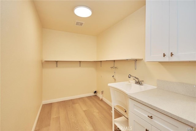 clothes washing area with cabinets, washer hookup, sink, and light hardwood / wood-style floors