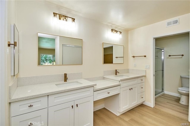 bathroom featuring toilet, vanity, wood-type flooring, and walk in shower