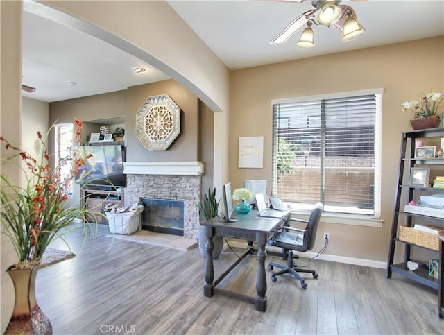 home office featuring ceiling fan, a fireplace, and hardwood / wood-style floors