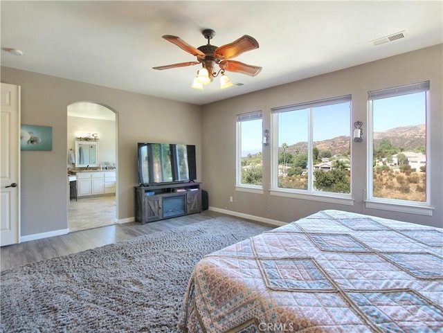 bedroom with ceiling fan, light hardwood / wood-style floors, and ensuite bathroom