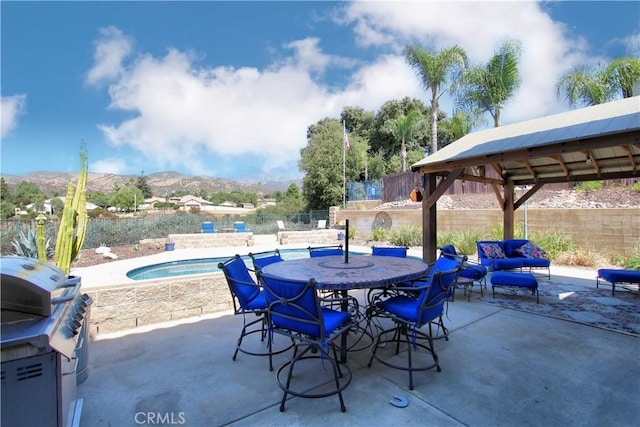 view of patio featuring a mountain view, a pool with hot tub, and grilling area