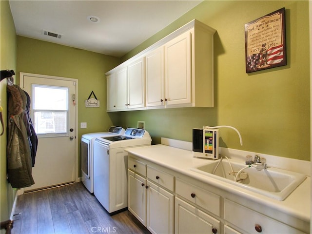 washroom featuring washing machine and dryer, dark hardwood / wood-style floors, sink, and cabinets